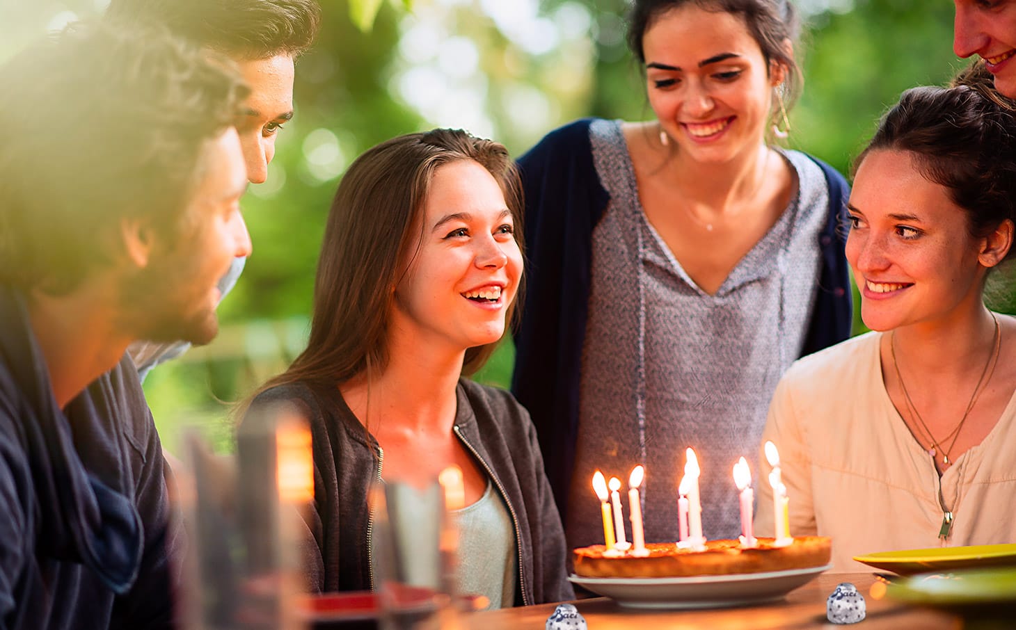 Una ragazza che festeggia il suo compleanno con amici, torta e candeline
